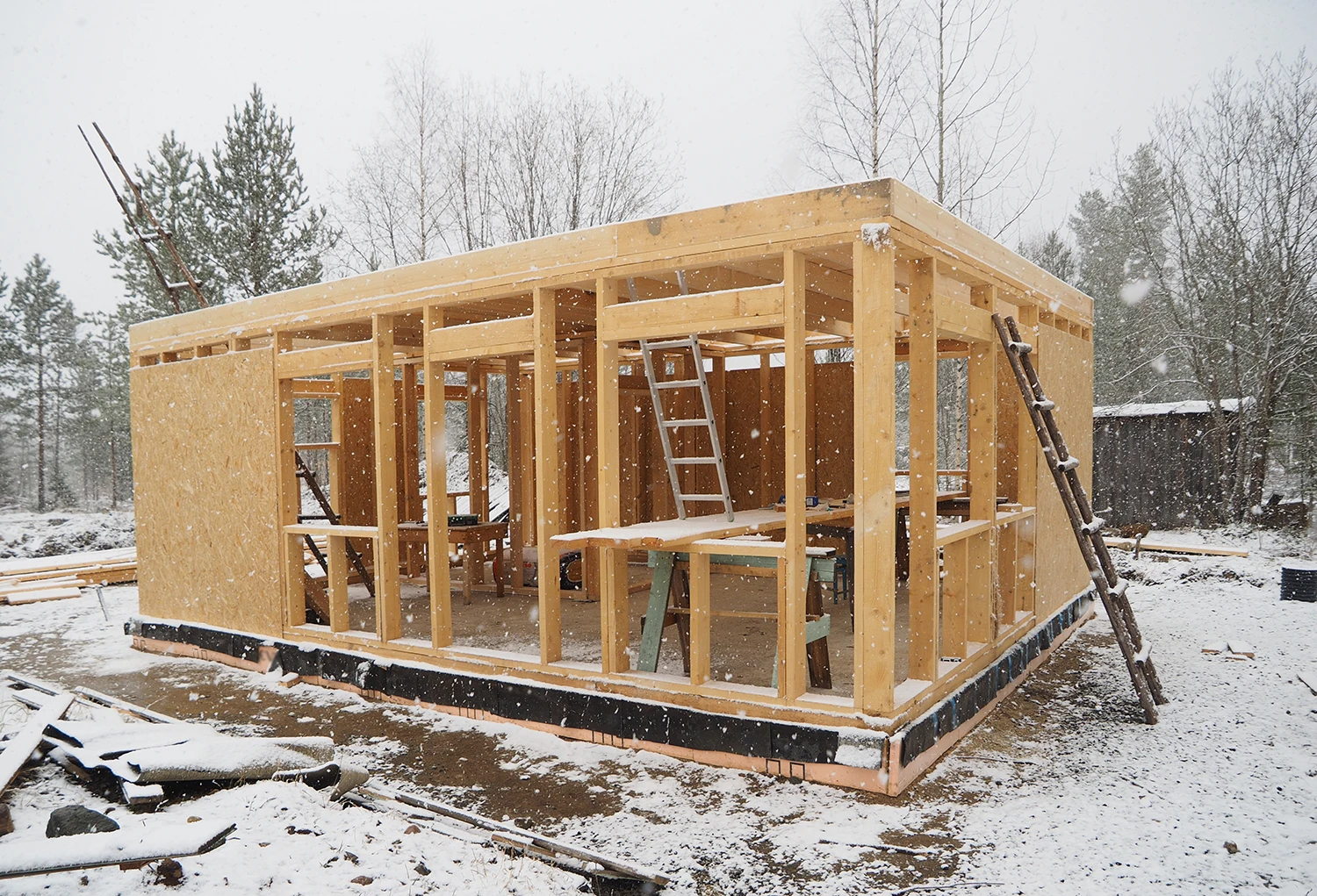 Wood frame house under construction in the winter with snow on the ground.