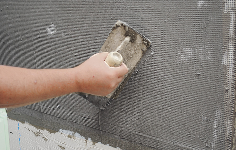 trowel moving over mesh on vertical wall