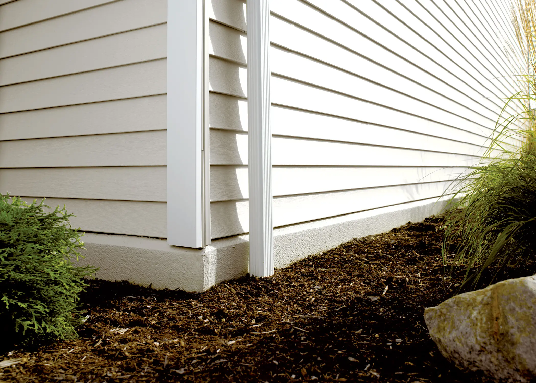 bottom corner of a house with siding and landscaping